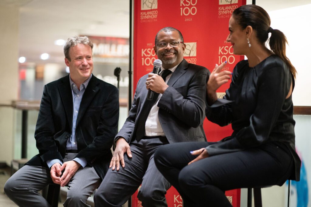 image shows three people talking with a microphone