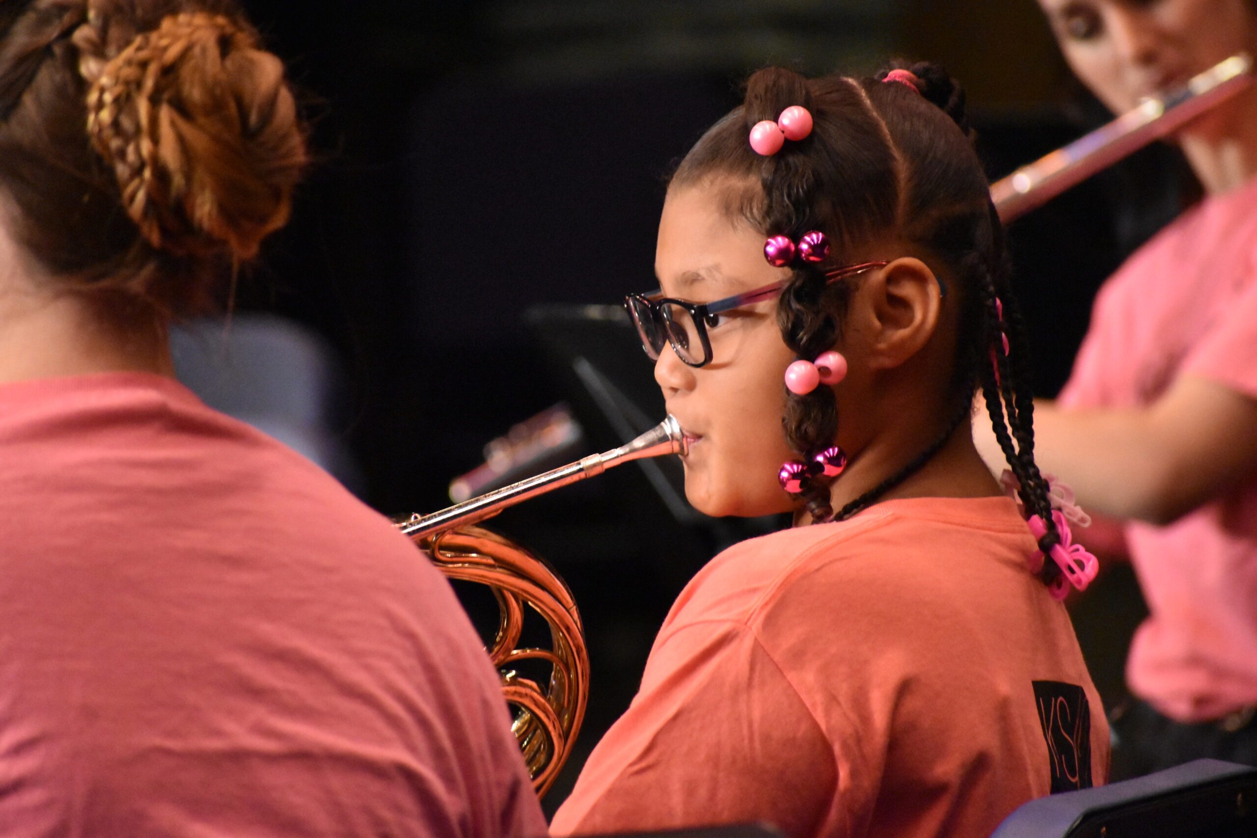 young girl with glasses and hair in twists plays the french horn