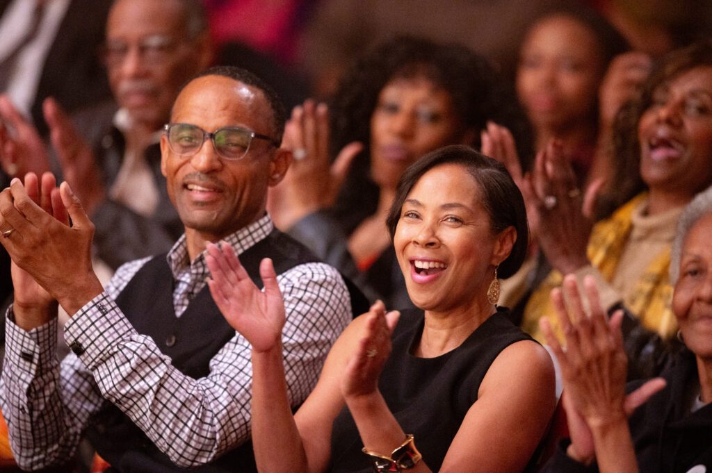 two people smile while clapping