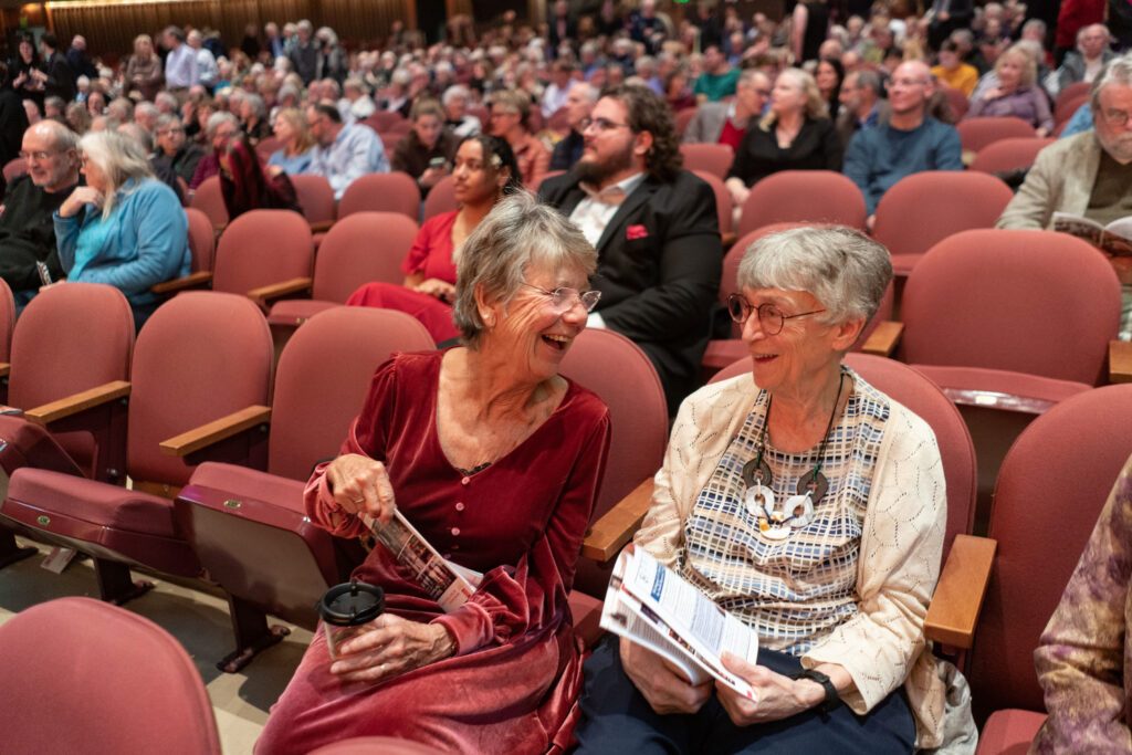 two ladies laugh with each other in the concert hall