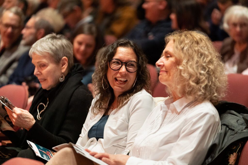 two women smile sitting in the concert hall