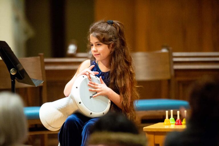 young girl plays drum in orchestra rouh