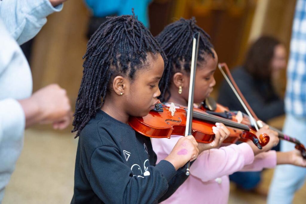 young girl plays violin at family discovery concert for all ages