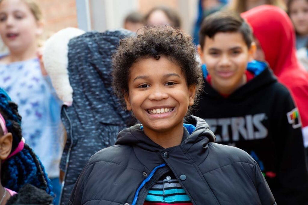 young student smiles while getting off the bus at the concert hall