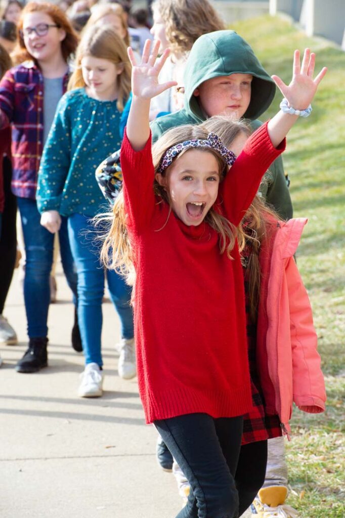 young girl raises hands in excitement